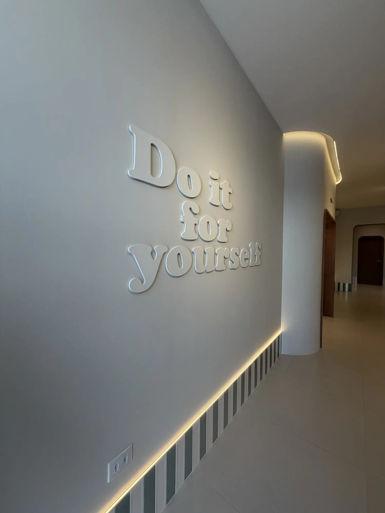 Parede do corredor com a frase Do it for yourself em relevo